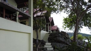 A staircase leading to a building with a red roof, surrounded by greenery and overlooking a body of water. - Sunrise Villas Seaview (Rayong)