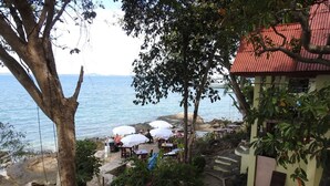 A coastal outdoor seating area with tables and umbrellas, overlooking the sea. - Sunrise Villas Seaview (Rayong)