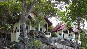 A two-story building with a red roof, surrounded by large rocks and trees. - Sunrise Villas Seaview (Rayong)