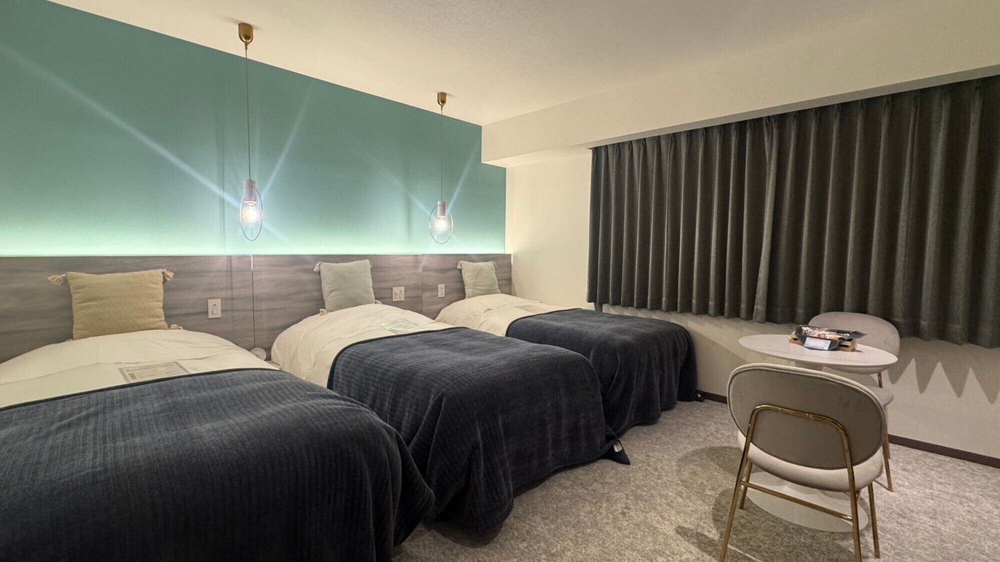 A hotel room with two beds, a small round table, and a chair.