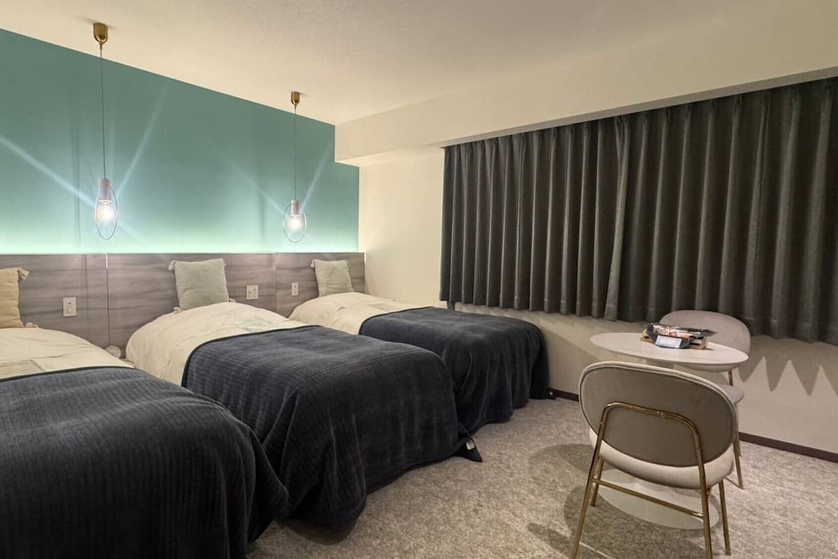 A hotel room with two beds, a small round table, and a chair.