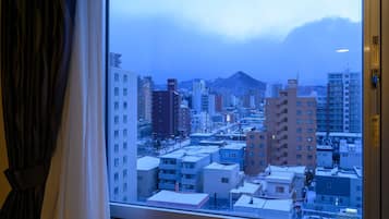 A view from a window overlooking a cityscape with multiple buildings, including high-rise apartments and smaller structures.
