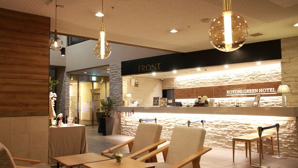 A hotel reception area with a stone wall, wooden furniture, and hanging pendant lights. - Kotoni Green Hotel (Sapporo)