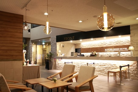 A hotel reception area with a stone wall, wooden furniture, and hanging pendant lights.