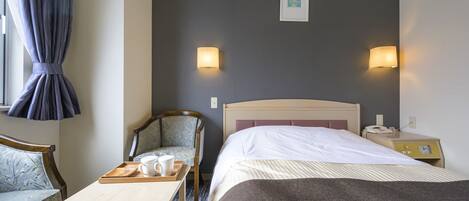 Een hotelkamer met een bed, een stoel, een klein tafeltje met een dienblad, en twee wandlampen.