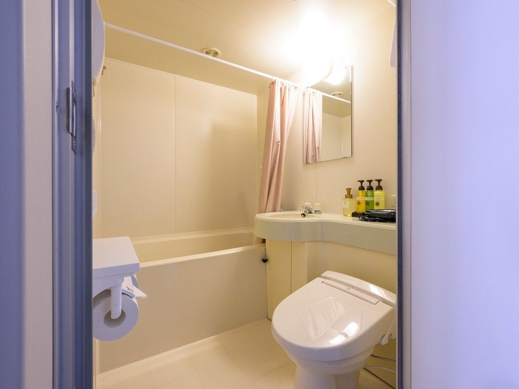 Une salle de bain comprenant des toilettes, un lavabo et un espace douche.