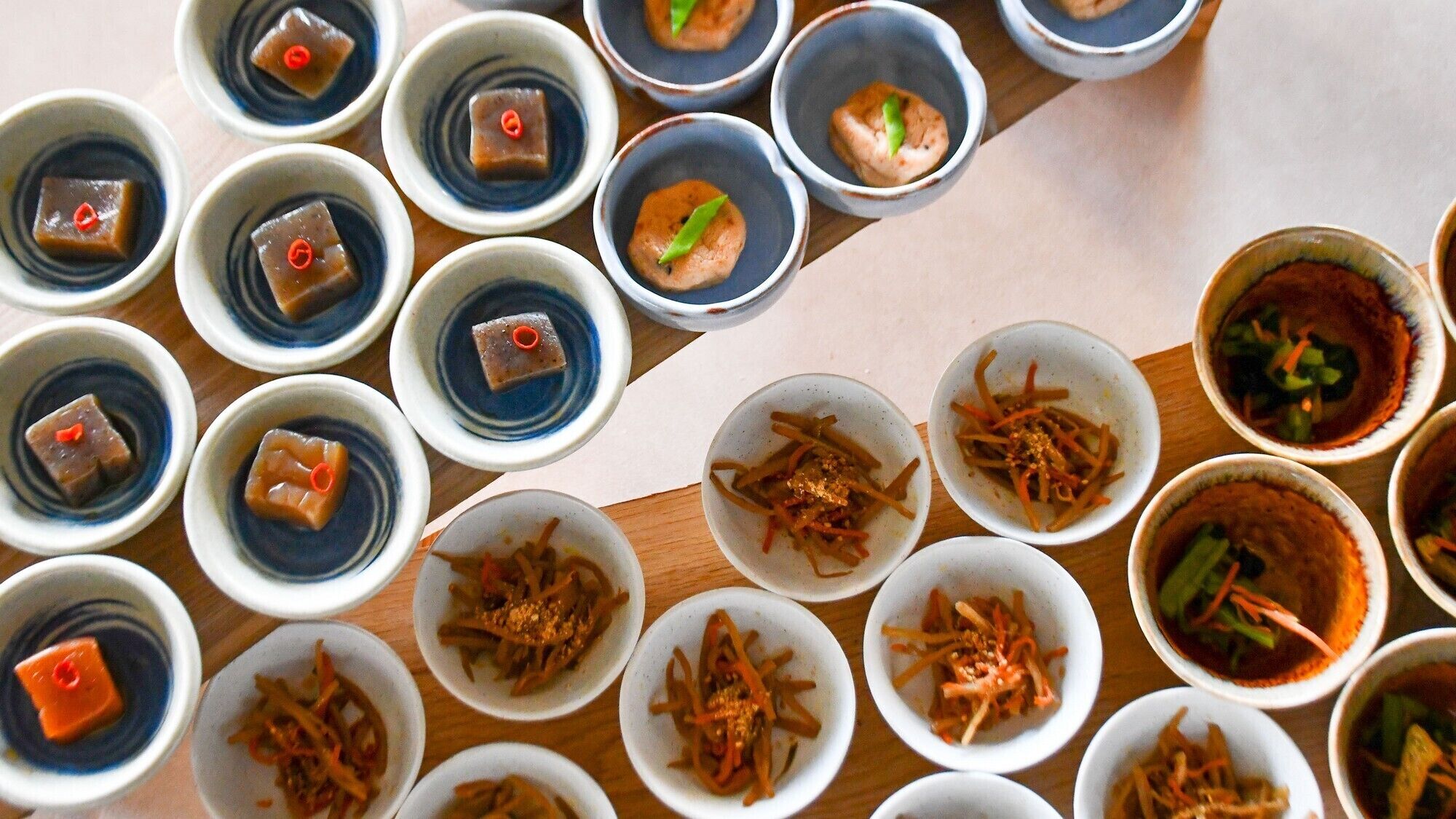 A variety of dishes arranged in small bowls on a wooden table.