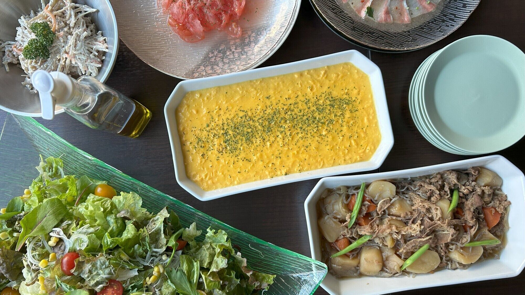 A table with various dishes including a salad, a creamy soup, and a meat dish.