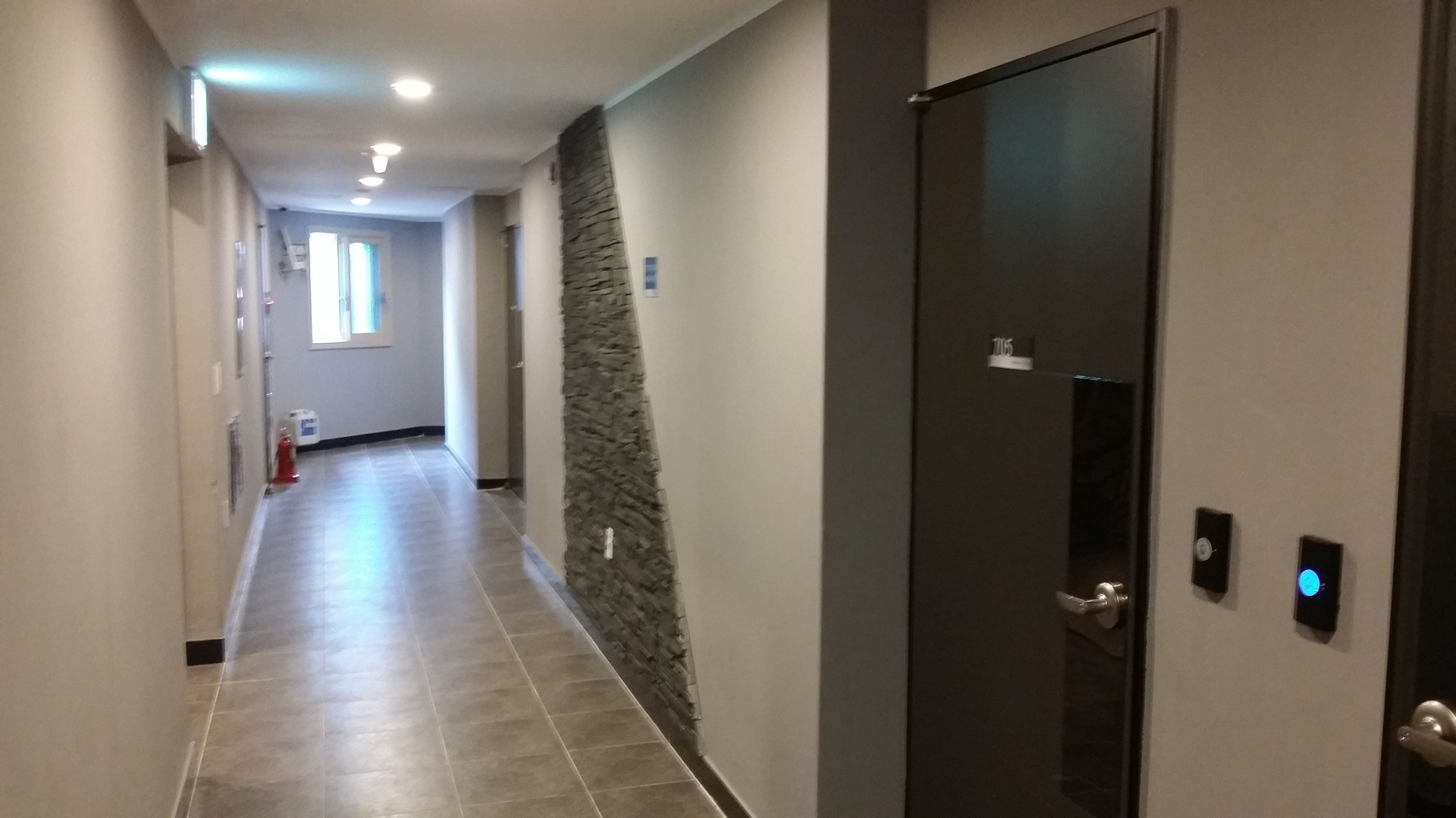 A hallway with a dark door, a stone accent wall, and a tiled floor.