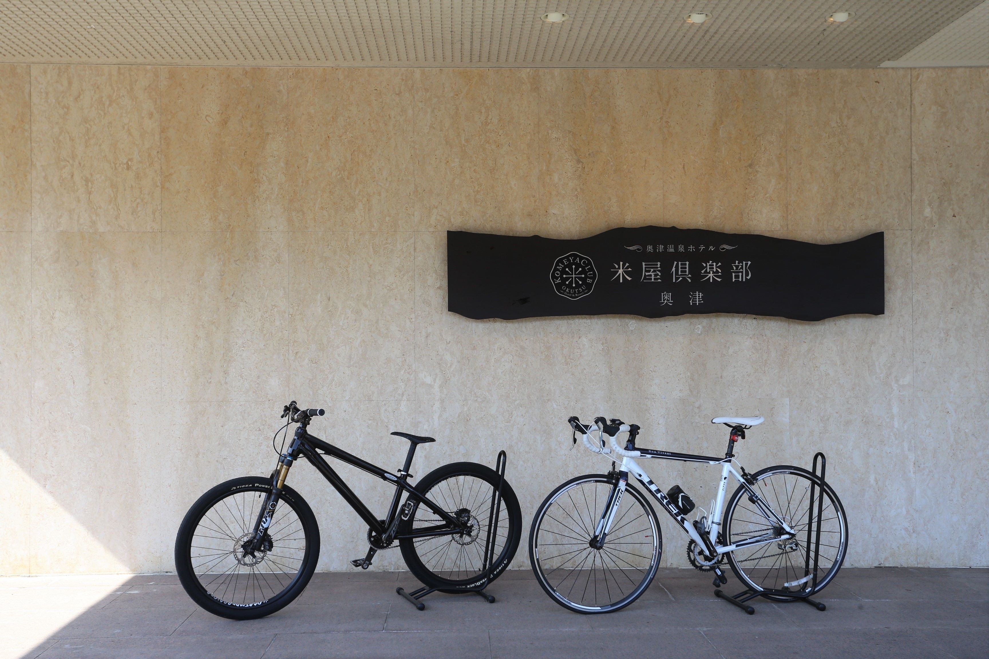 Due biciclette parcheggiate contro un muro con un cartello sopra.