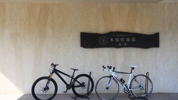 Due biciclette parcheggiate contro un muro con un cartello sopra.