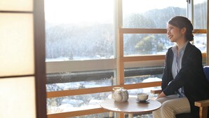 A person seated by a window with a view of a snowy landscape. - Komeyaclub Okutsu (Kagamino)