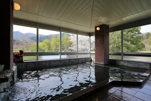 A large indoor swimming pool with a view of mountains and trees through large windows. - Komeyaclub Okutsu (Kagamino)
