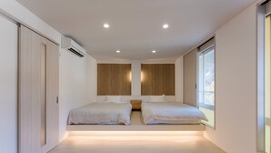 A modern bedroom with two beds, a wooden headboard, a nightstand, and a large window. - Komeyaclub Okutsu (Kagamino)