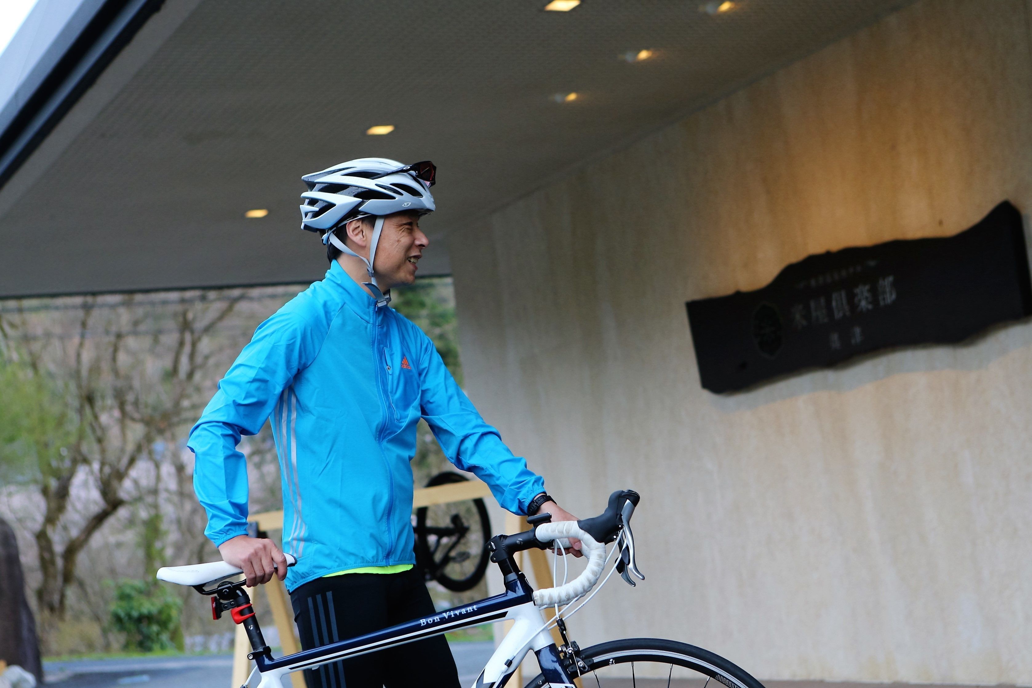 A person in a blue jacket and helmet standing next to a bicycle.