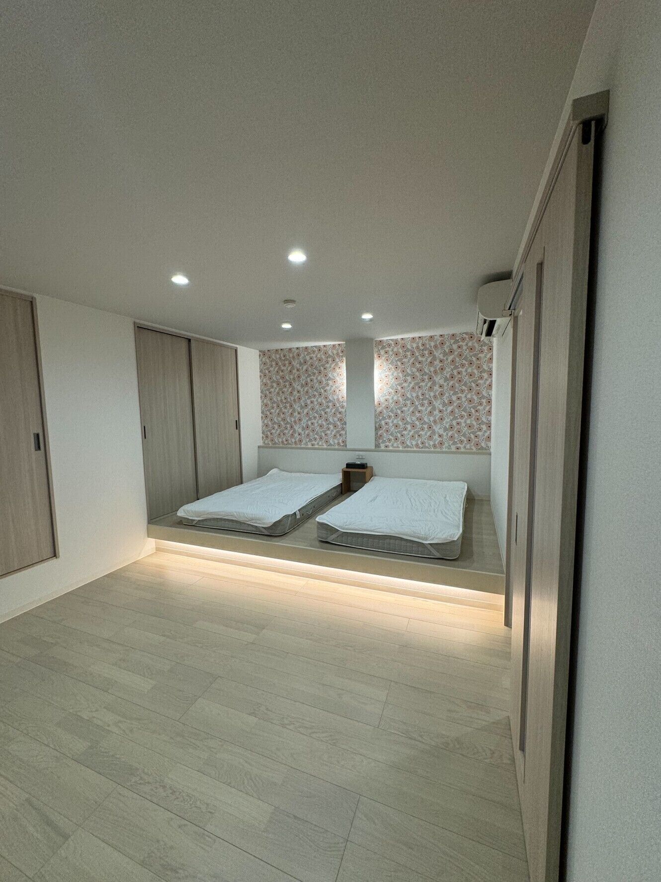 Un dormitorio con dos camas individuales, un armario y una mesita de noche.
