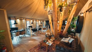 A spacious tented living area with a sofa, coffee table, and dining setup.
