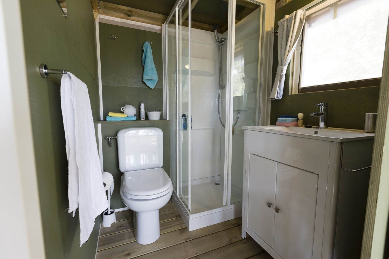 A compact bathroom with a toilet, shower, and sink.