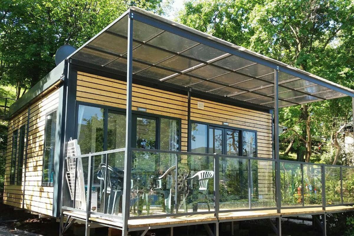 Een moderne chalet met grote ramen, een glazen balkon en een houten gevel.