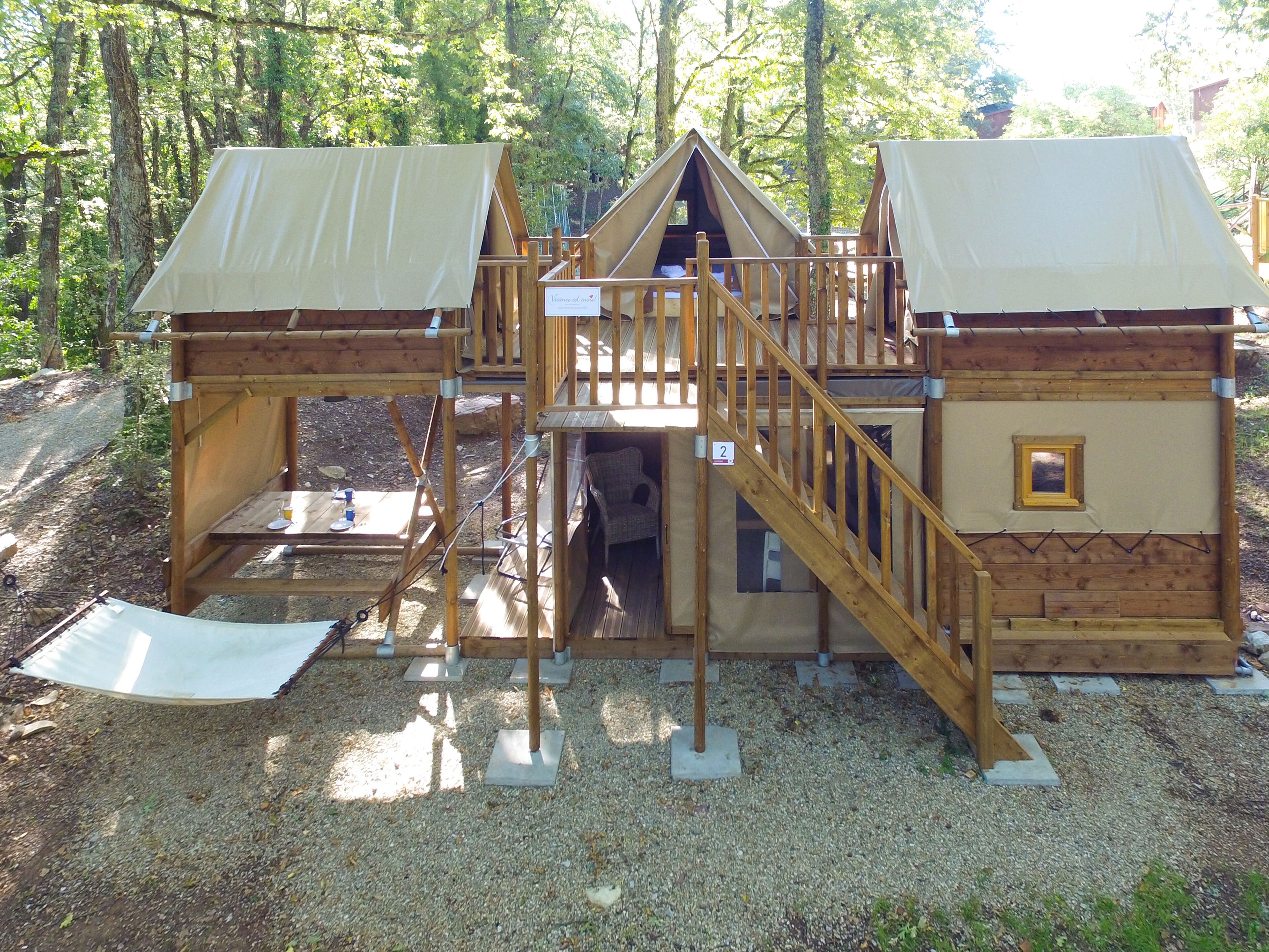 A wooden cabin with a balcony, a staircase, and a small window.