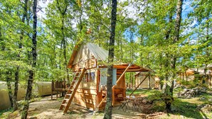 A wooden cabin with a ladder, a small porch, and a table with chairs.