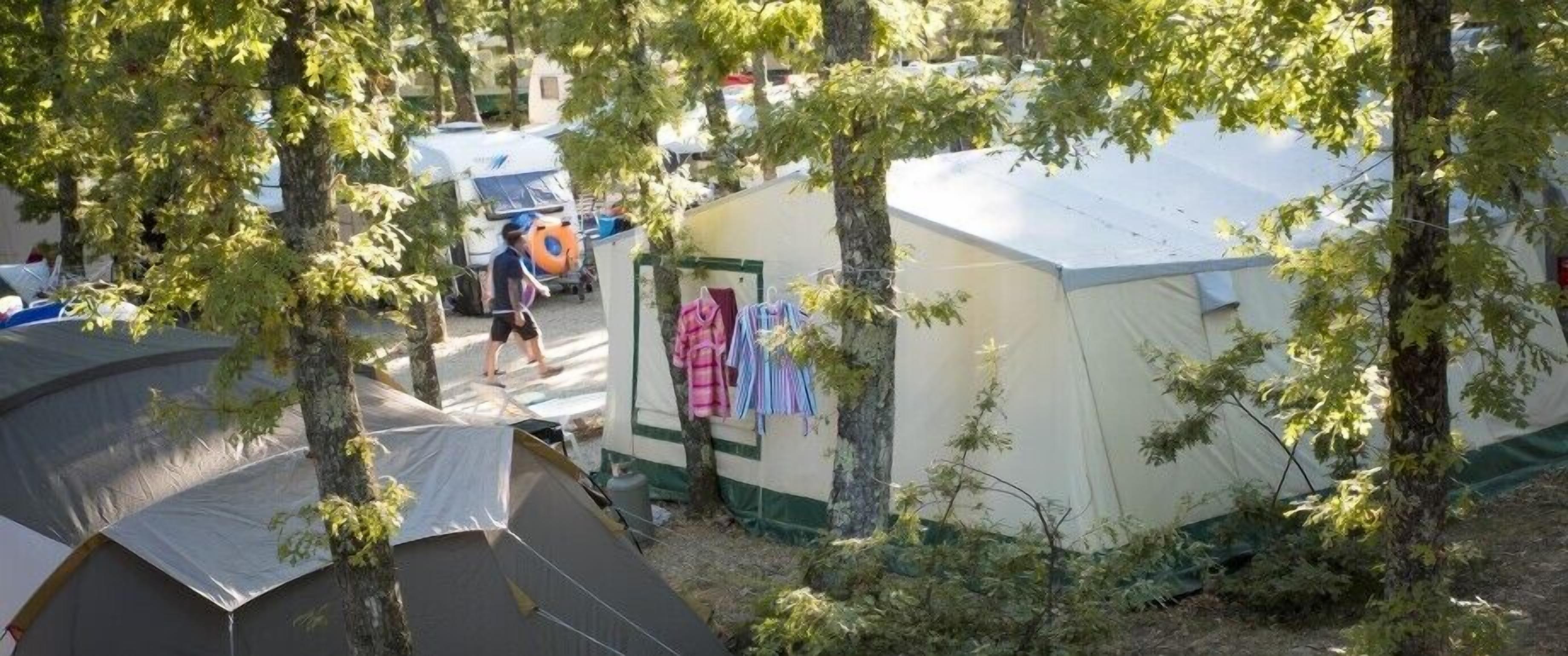 Un terrain de camping avec des tentes et un petit bâtiment dont les vêtements sont étendus à l’extérieur.