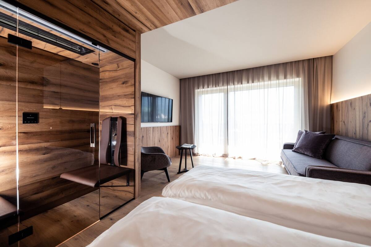 Een moderne hotelkamer met een houten plafond, een groot bed, een bank, een televisie en een kleine tafel.