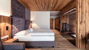 Un dormitorio moderno con techo de madera, una cama con ropa de cama blanca, una mesita de noche y una silla.