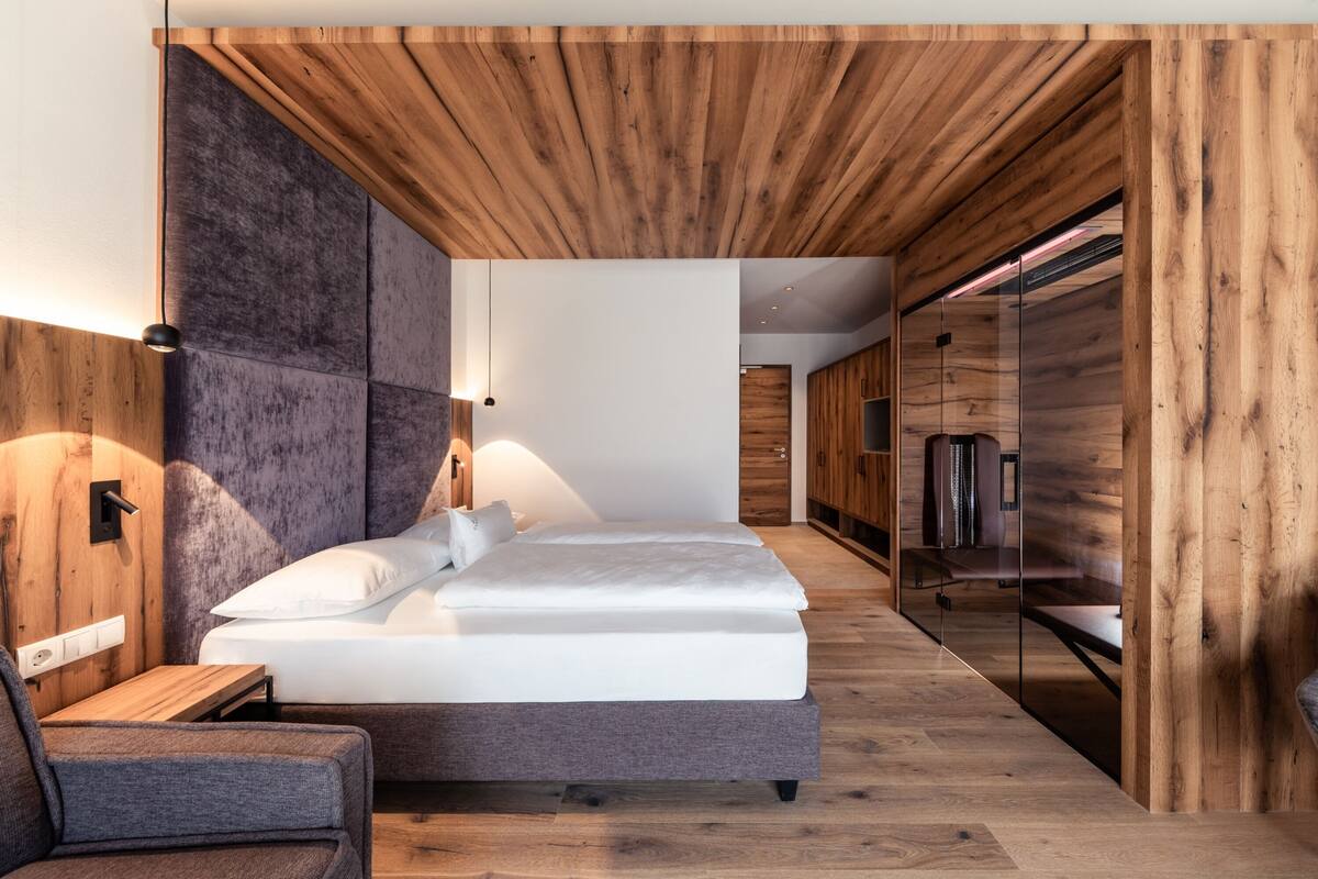 Een moderne slaapkamer met een houten plafond, een bed met wit beddengoed, een nachtkastje en een stoel.