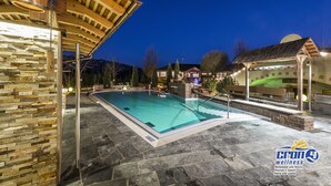 Una piscina con paredes de piedra y una pérgola de madera.
