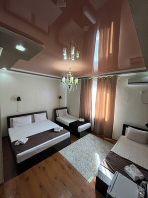 A hotel room with two beds, a chandelier, an air conditioning unit, and a wooden floor. - Euro Asia Hotel in Ichan Kala (Khiva)