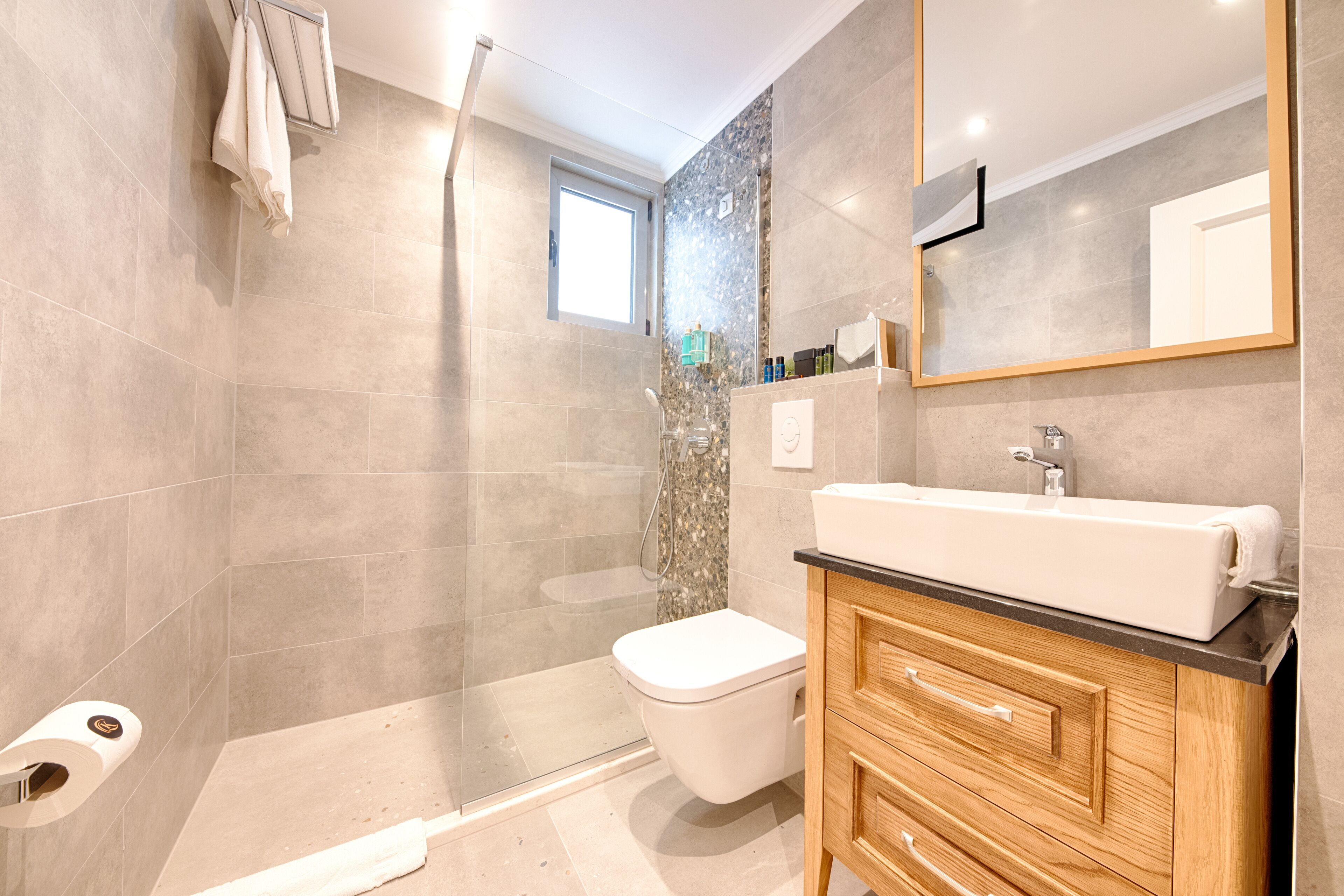 Een moderne badkamer met douche, toilet en wastafel.
