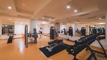 A gym with various exercise equipment, including dumbbells, a bench, and weight machines.