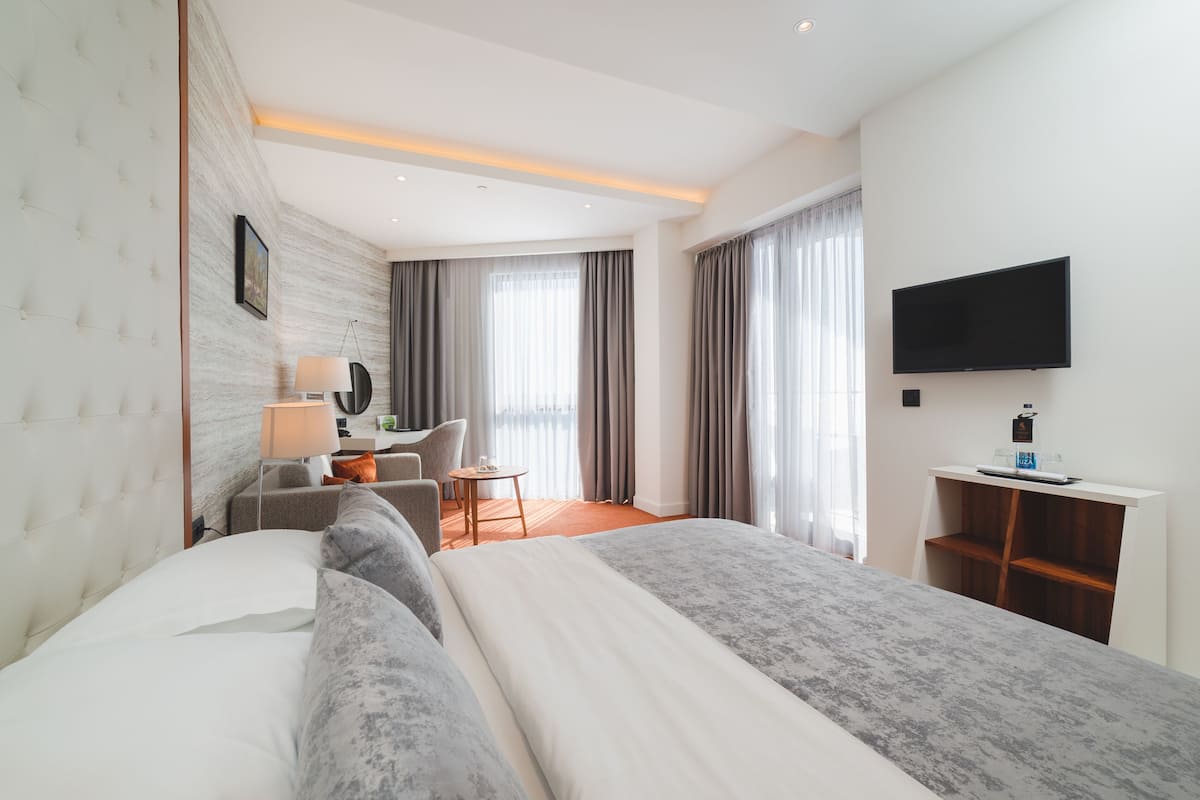Una habitación de hotel moderna con una cama grande, un escritorio, una silla y un televisor.