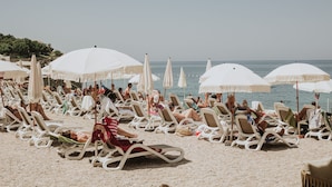 A beach with rows of sun loungers and white umbrellas. - Kalamper Hotel & Spa (Bar)