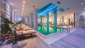 Une piscine intérieure dotée de chaises longues et d’un système d’éclairage au plafond.