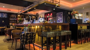 A bar area with multiple stools, a counter, and a staircase leading to an upper level.