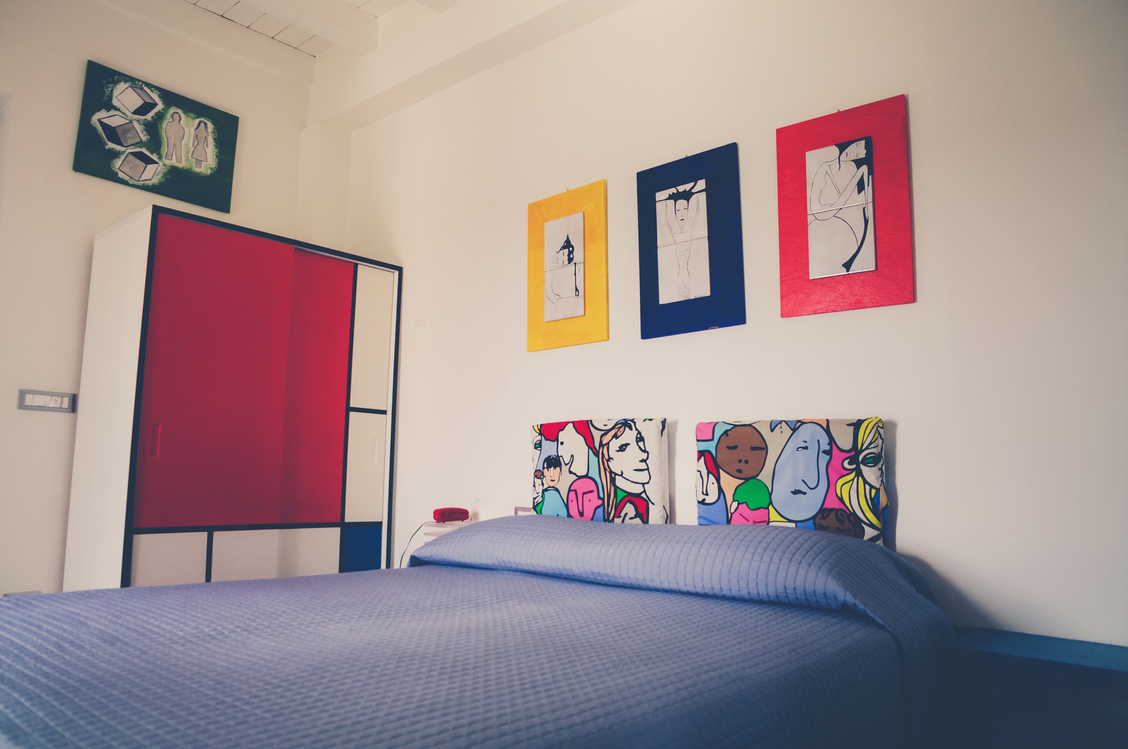 Un dormitorio con cama, armario y tres cuadros en la pared.