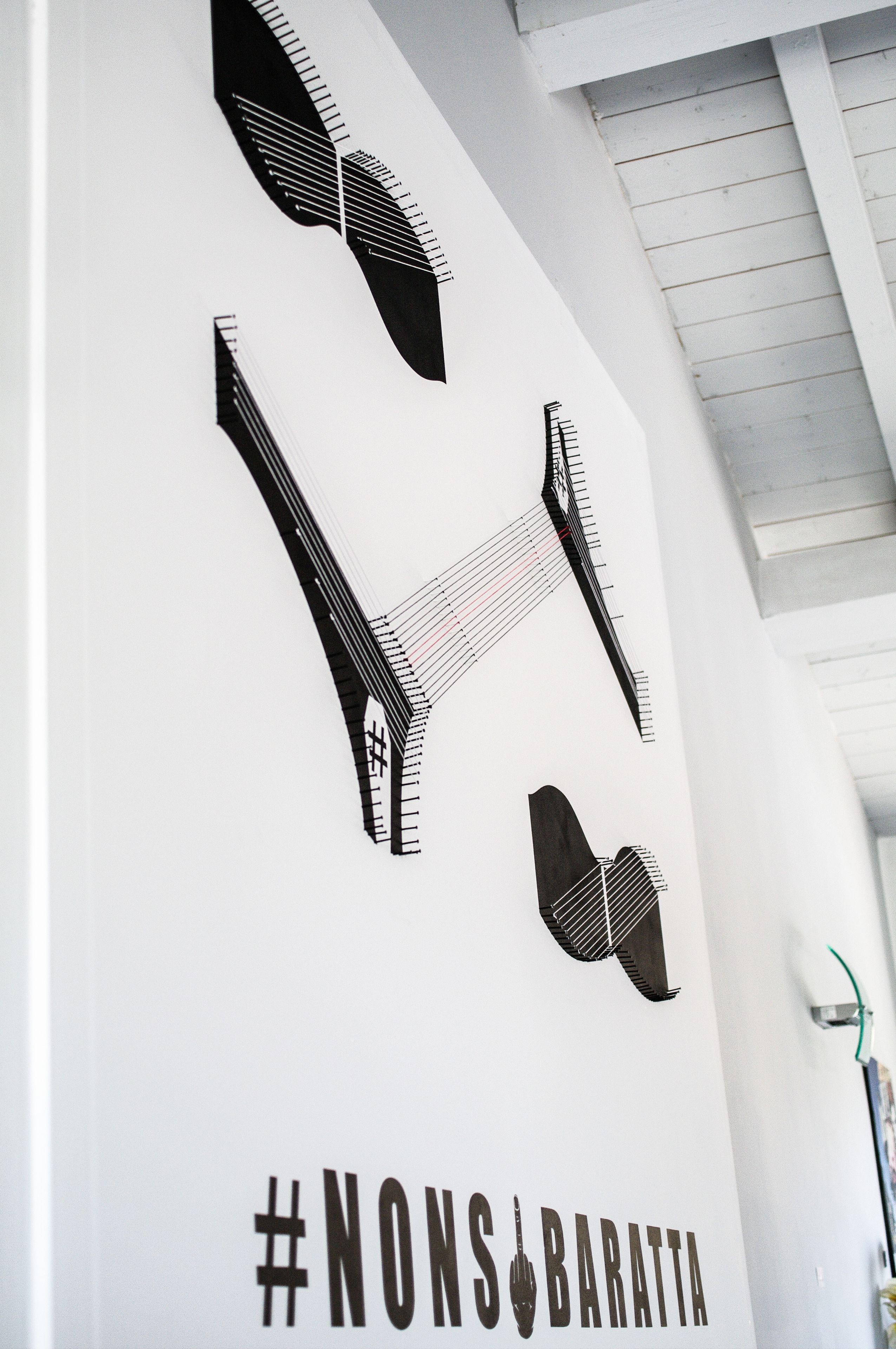 A wall with abstract black and white designs and the hashtag #NONS_BARATTA.