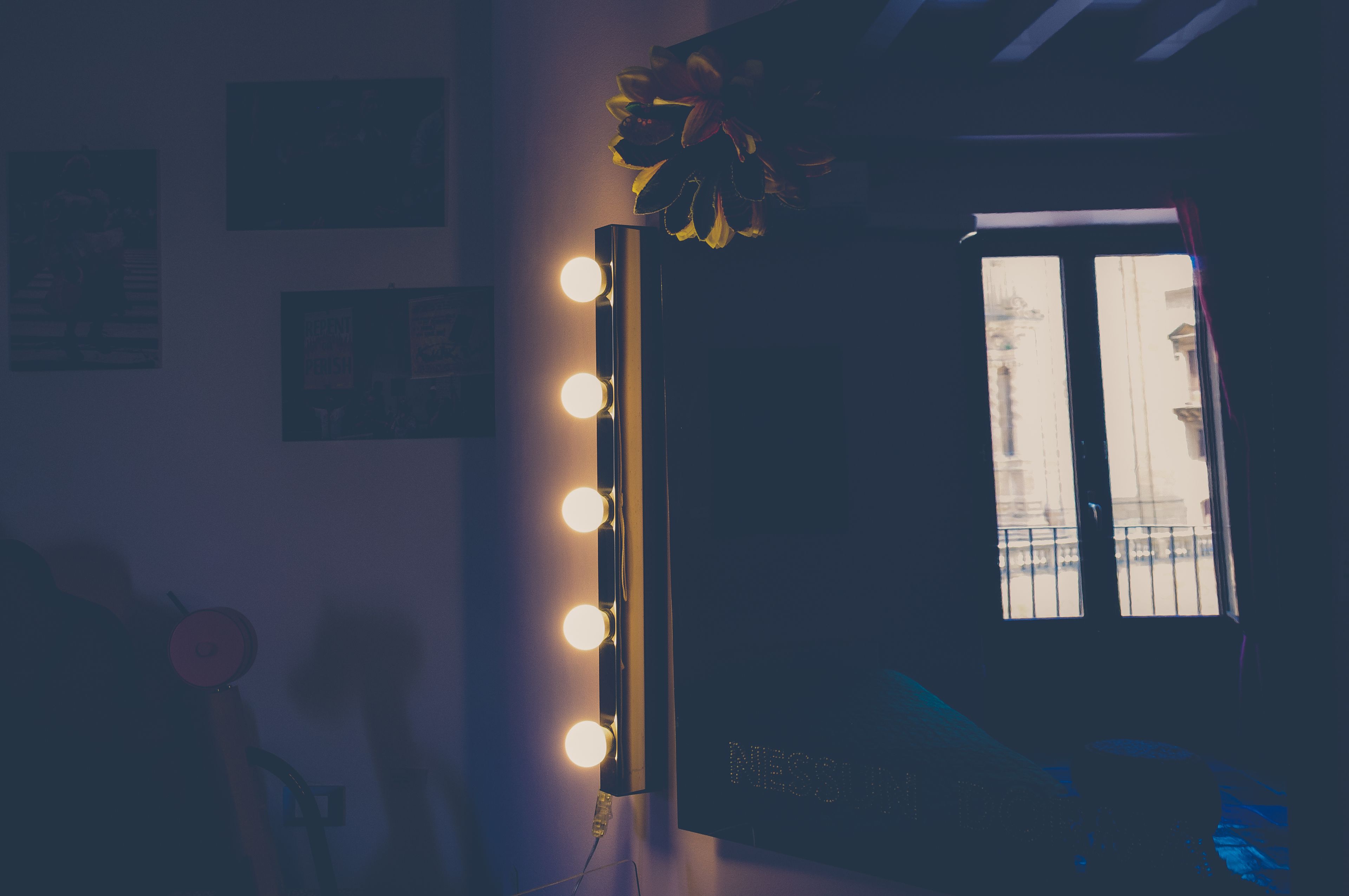 Una habitación con espejo, luces y una puerta con vistas.