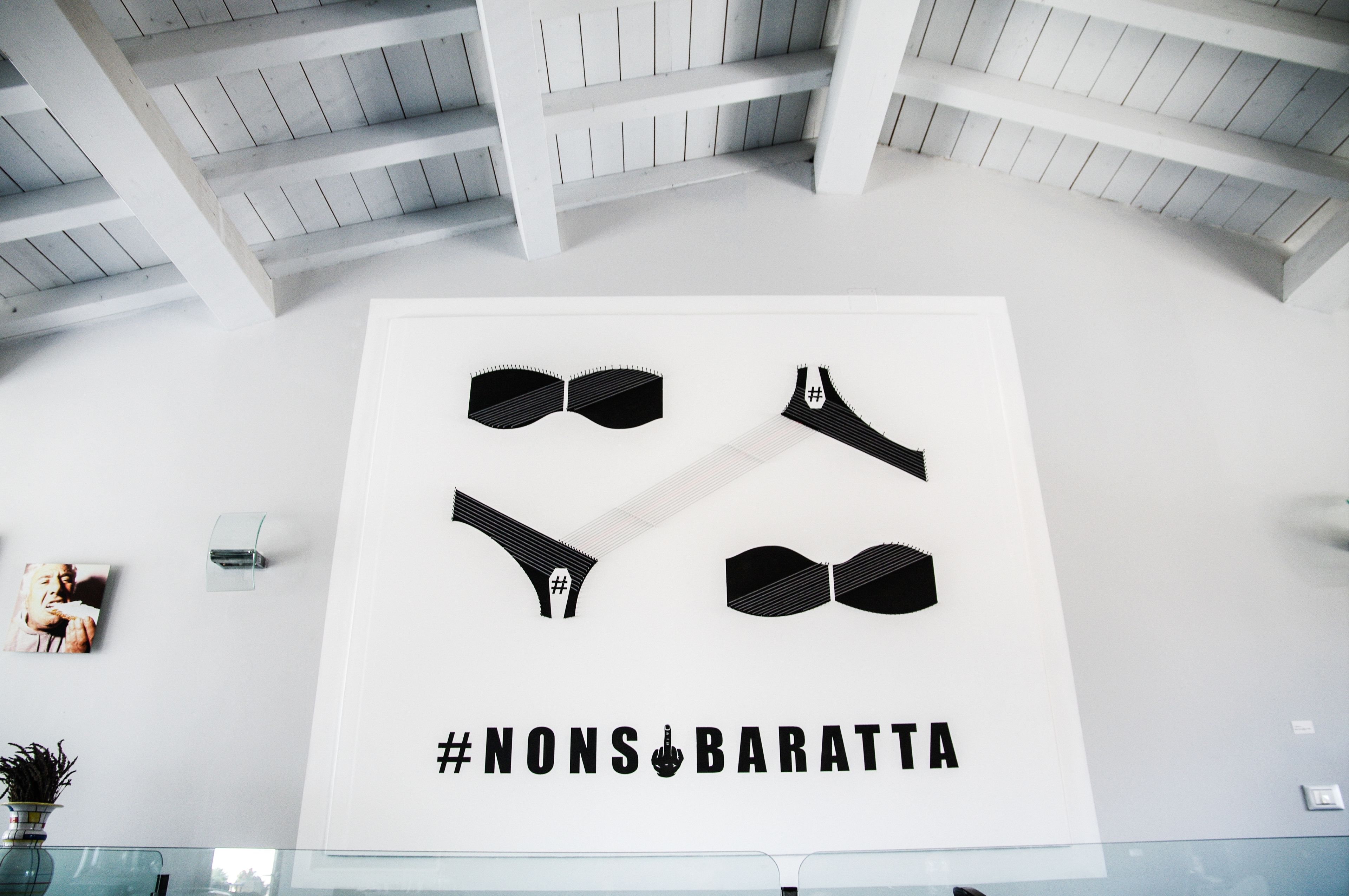 A wall with #NONS&BARATTA text and bowtie-shaped cutouts.