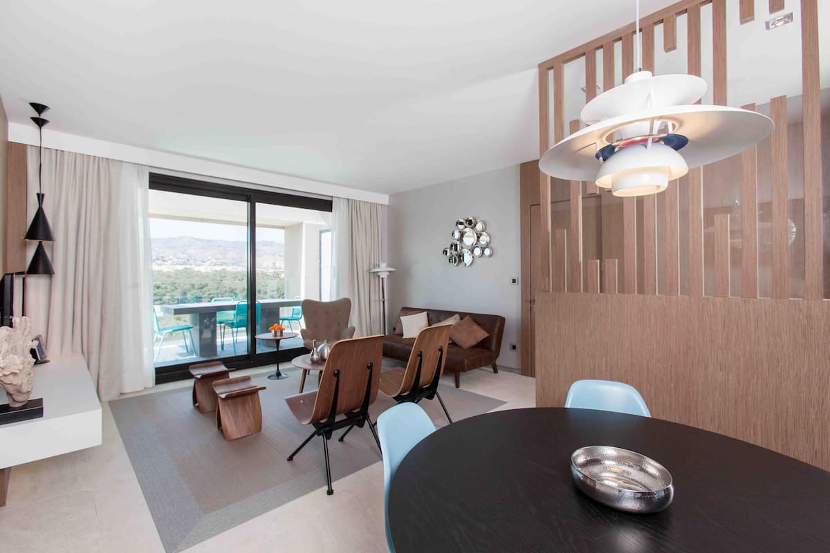 Ein modernes Hotelzimmer mit Essbereich, einer Couch und Blick ins Freie.