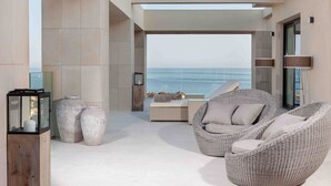 Un espace de détente moderne avec des fauteuils en osier, une table en verre et de grands vases.
