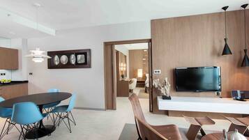 A modern kitchen with a dining area, a TV, and a wooden accent wall.