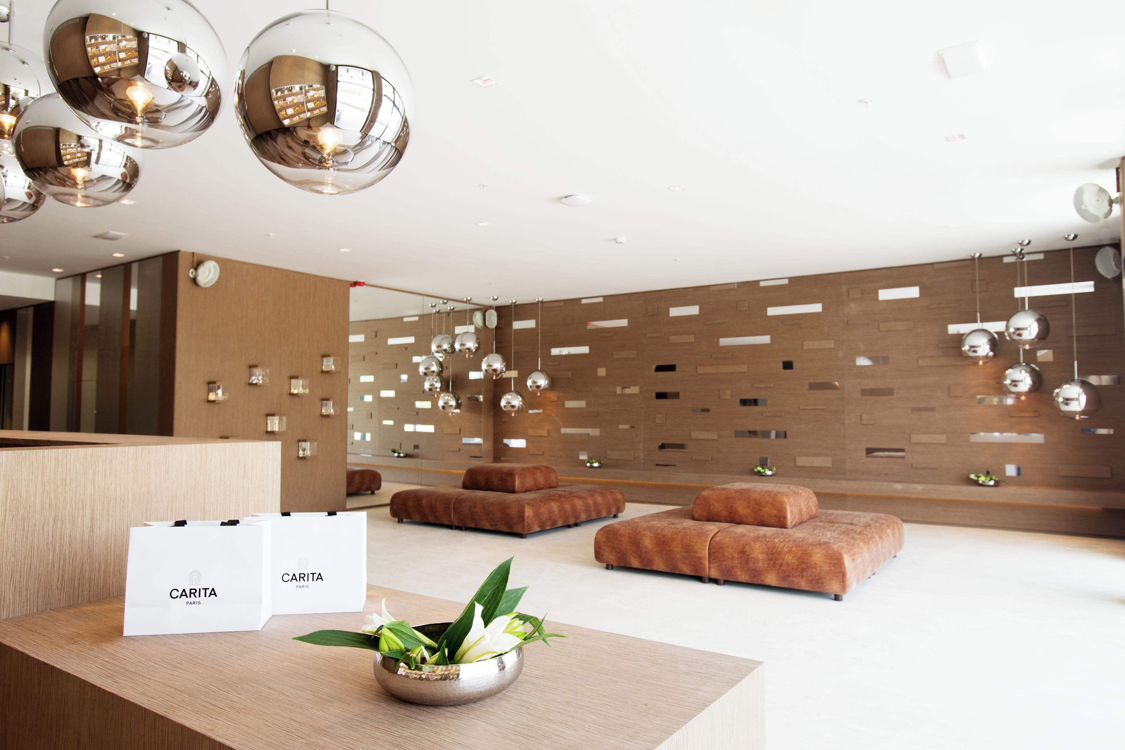Un área de recepción moderna con un mostrador de madera, dos sofás y un cuenco decorativo con plantas.