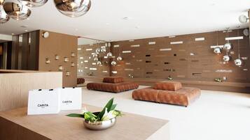 Un área de recepción moderna con un mostrador de madera, dos sofás y un cuenco decorativo con plantas.