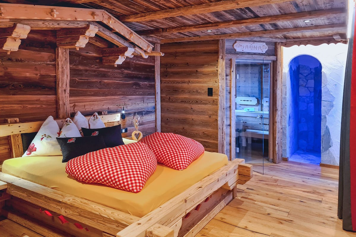 Ein Zimmer in einer Holzhütte mit einem Bett, Kissen und einer hölzernen Bank.