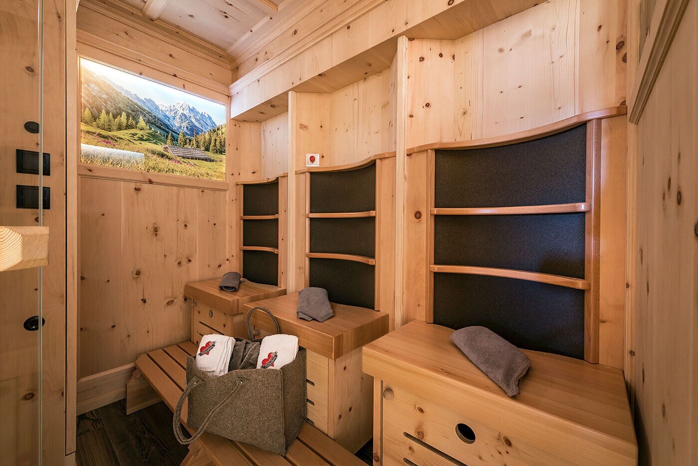 A wooden sauna room with benches, towels, and a basket of towels.