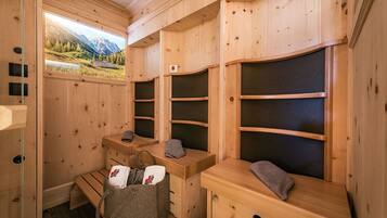 A wooden sauna room with benches, towels, and a basket of towels.