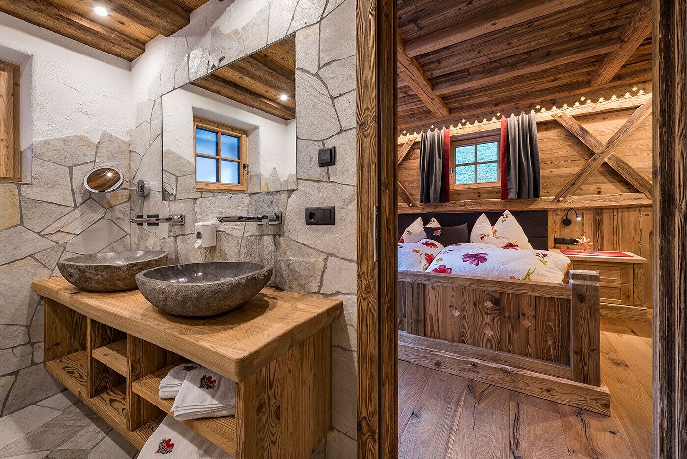 Un baño rústico con lavamanos de piedra, tocador de madera y pared espejada.